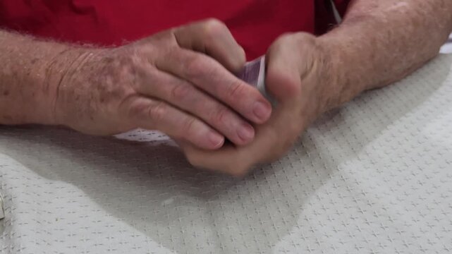 elderly man shuffling a deck of playing cards