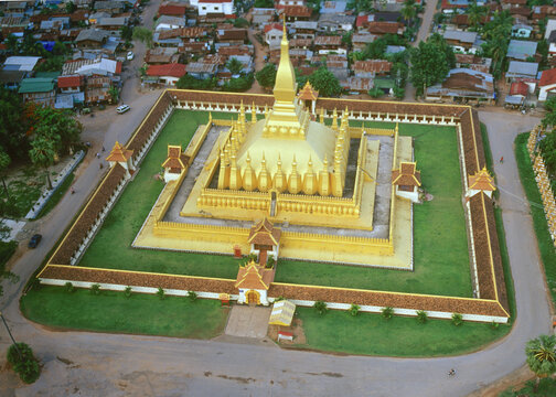 Vientiane, Laos - 09 November 2004: Aerial view of the golden Pha That Luang temple complex surrounded by a square wall and lush green lawns in the city center.