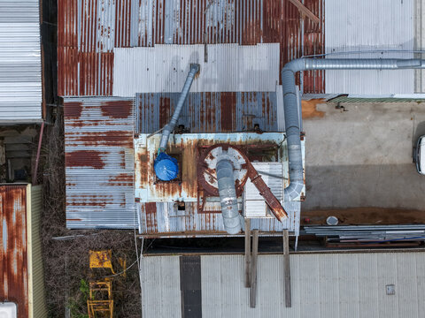 Melbourne, VIC, Australia - 25 September 2026: Aerial view of industrial factory site with rusted corrugated metal roofs, ventilation pipes, and machinery.