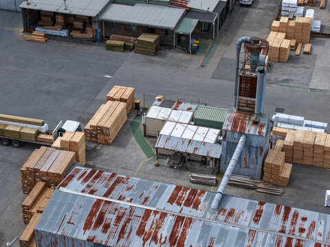 Melbourne, VIC, Australia - 25 September 2026: Aerial view of a timber processing facility with stacks of lumber, industrial machinery, and corrugated metal rooftops.