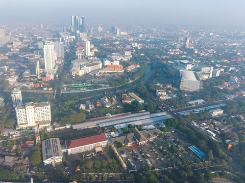Surabaya, Indonesia - 05 August 2026: Aerial view of the urban landscape of Surabaya, featuring high-rise buildings, a winding river, and the railway station.