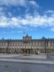 Royal Palace of Madrid facade under bright blue sky with clouds in Plaza de la Armeria © JaneM