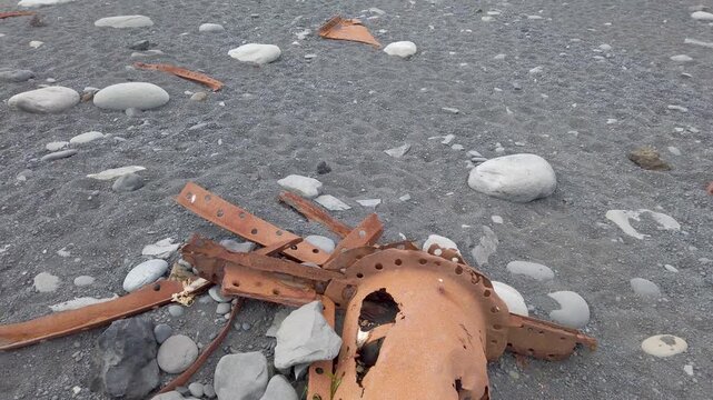 Rusty remains of the Epine trawler, wrecked in 1948, scattered among pebbles on Djupalonssandur black beach, Snaefellsnes, Iceland.