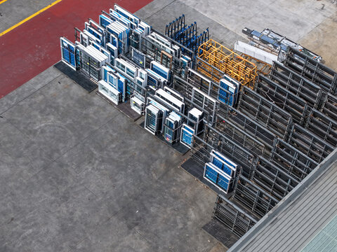 Melbourne, VIC, Australia - 25 September 2026: Aerial view of a storage yard filled with rows of window frames and industrial metal racks on a concrete surface.