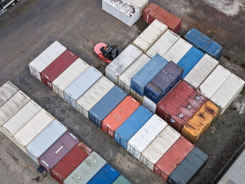 Melbourne, VIC, Australia - 25 September 2026: Aerial view of colorful shipping containers arranged in rows at a logistics yard, with a forklift operating nearby.