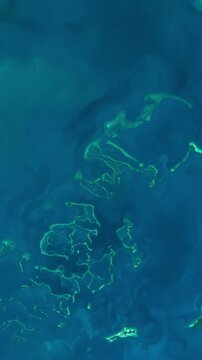 View from above on atolls in azure sea in tropical area. Camera is zooming in, rotating counterclockwise. Vertical video. Animation based on image by NASA