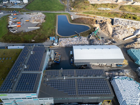 Oulu, Pohjois-Pohjanmaa, Finland - 25 September 2026: Aerial view of Rusko waste center with industrial buildings, solar panels, a retention pond, and sorted waste materials.