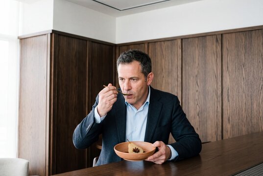 Middle-aged businessman in an elegant suit enjoying a gourmet poached pear dessert at a luxury restaurant table