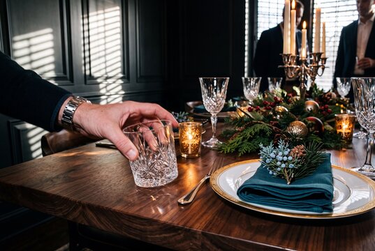 Man reaching for a crystal glass on an elegantly decorated festive Christmas dinner table