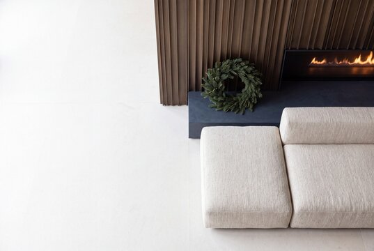 Minimalist living room interior with contemporary modular sofa modern fireplace and evergreen festive wreath