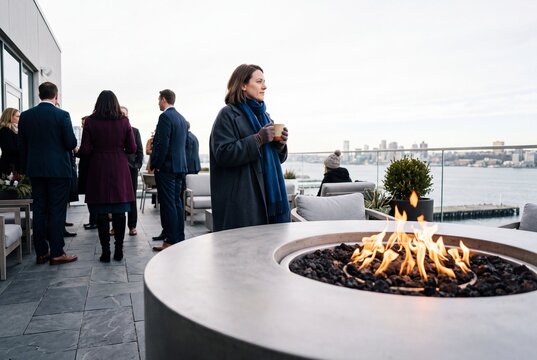 Business people gathering on an outdoor rooftop terrace with a modern fire pit overlooking the city skyline