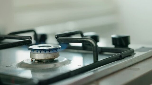 Person lighting gas stove and placing pink moka pot coffee maker on burner in kitchen.