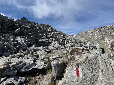 Mountain hiking route in the Swiss Alps in the canton of Uri and the Gotthard massif, showing official trail markings, rocky paths, rugged mountain terrain and dramatic high-altitude alpine scenery