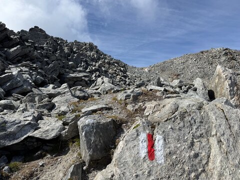 Mountain hiking route in the Swiss Alps in the canton of Uri and the Gotthard massif, showing official trail markings, rocky paths, rugged mountain terrain and dramatic high-altitude alpine scenery