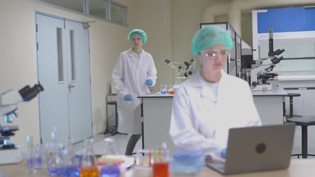 Two lab technicians work together in a modern laboratory with microscopes and samples during a research session