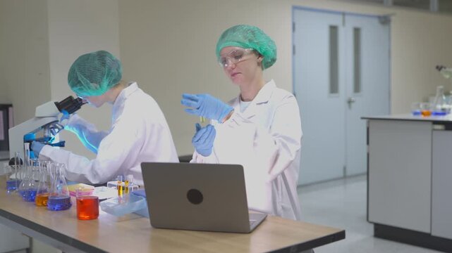 Two lab technicians work together in a modern laboratory with microscopes and samples during a research session
