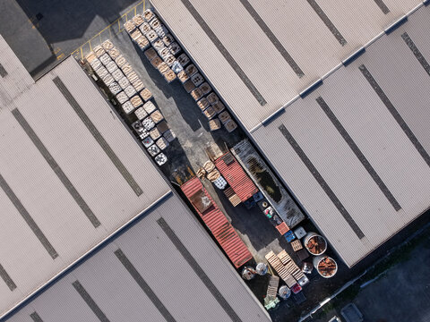 Melbourne, VIC, Australia - 22 September 2026: Aerial view of industrial factory rooftops in Kilsyth with shipping containers, wooden pallets, and storage drums in a loading area.