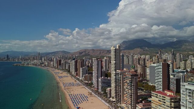 Aerial view of Benidorm coastline featuring skyscrapers sandy beach and Mediterranean sea in Spain under sunny sky.