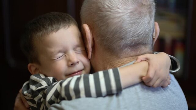 Great-grandson embraces elderly great-grandfather, showing tender intergenerational family bond and affection at home.