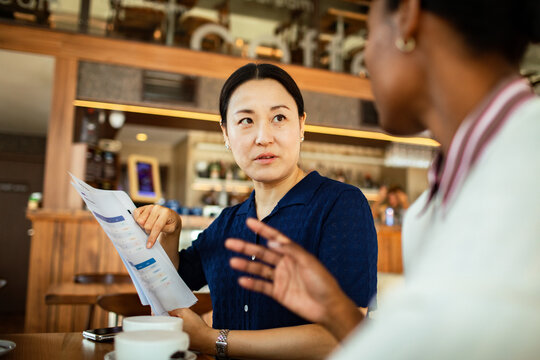 Woman pointing at report during cafe meeting