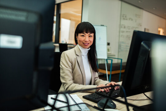 Smiling businesswoman typing at desktop computer in office