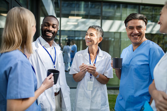 Smiling medical team chatting over coffee outdoors