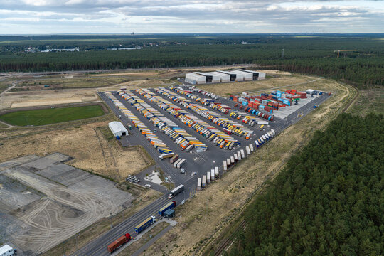 Grunheide Mark, Germany - 07 September 2026: Aerial view of Trailer Yard North with numerous semi-trailers parked in rows, shipping containers, and surrounding forest landscape.