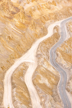 Geamana, Romania - 21 September 2026: Aerial view of the winding dirt roads and steep terraced slopes of the Geamana mining site with its distinctive yellow and grey earth textures.
