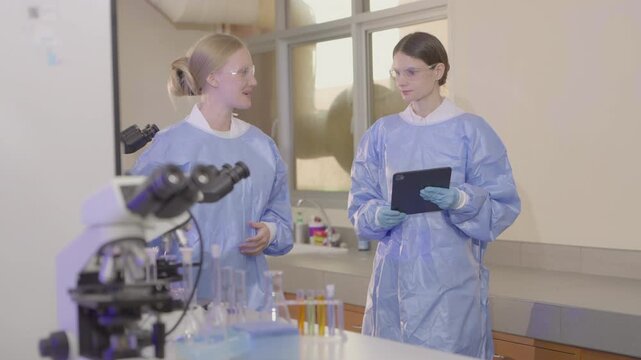 Two lab technicians work together in a modern laboratory with microscopes and samples during a research session