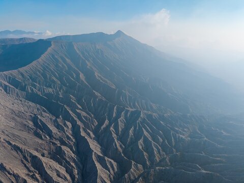 Aerial view of Mount Bromo showing the dramatic volcanic landscape with deep ridges and rugged terrain in Tosari, East Java, Indonesia.