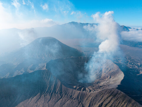 Aerial view of Mount Bromo crater with volcanic smoke rising against a clear blue sky in the Tengger Caldera, Tosari, East Java, Indonesia.