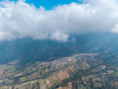 Aerial view of Wonokerto village nestled in the mountains of East Java, featuring terraced fields and scattered houses in Sukorejo, East Java, Indonesia.
