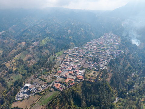 Aerial view of Wonokerto village nestled among lush green hills and agricultural fields in Sukorejo, East Java, Indonesia.