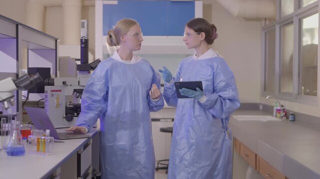 Two lab technicians work together in a modern laboratory with microscopes and samples during a research session