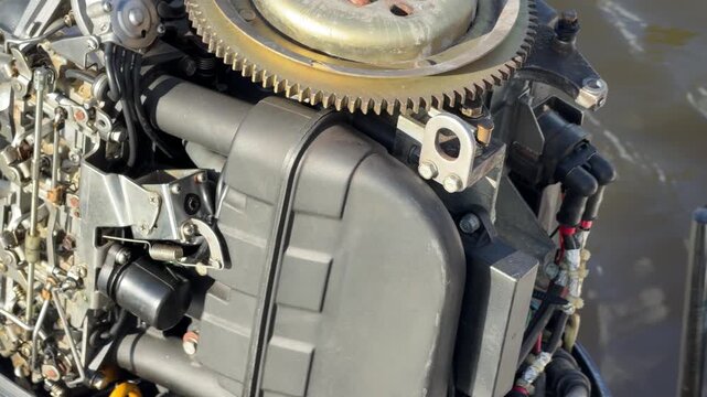 Detailed view of the internal mechanical parts and flywheel of a disassembled outboard boat engine outdoors.