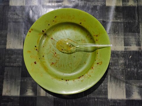 Empty green plastic plate with a dirty spoon after a meal