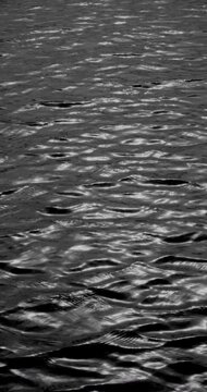 Natural water surface shot on camera. Water surface shimmers in real shooting on camera showing small waves and silver highlights. 