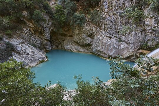 A turquoise pool in a rocky setting with dense vegetation and a peaceful atmosphere, waterfalls, ponds, Polylimnio, Peloponnese, Greece