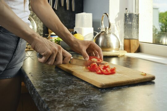 Chopping tomatoes on wooden cutting board in kitchen during daylight