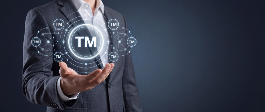 Professional businessman holding a glowing digital trademark TM icon, symbolizing brand protection, intellectual property rights, corporate identity legal security and patent registration concept
