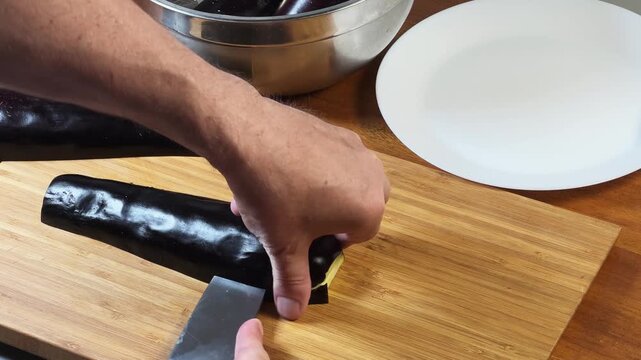 Slicing eggplant lengthwise into long strips on a cutting board