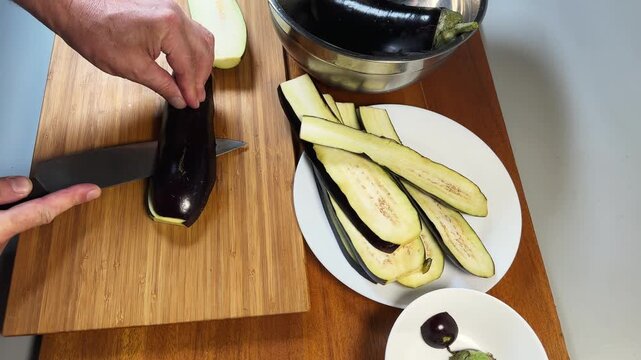 Slicing eggplant lengthwise into long strips on a cutting board