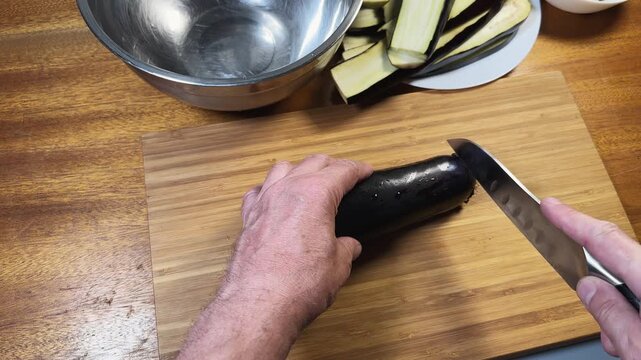 Cutting eggplant lengthwise into two halves on a cutting board