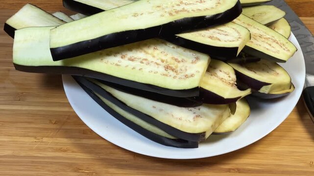 Long slices of purple eggplants cut lengthwise on a plate