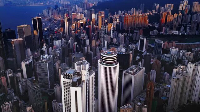 Dense highrise cluster in Kowloon with narrow urban streets and vertical facades filmed by drone. Rooftop machinery and terraces and close packed towers form grid. Aerial view of industrial undertone