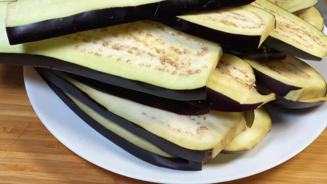 Long slices of purple eggplants cut lengthwise on a plate