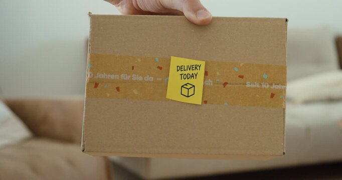 Hand holds a cardboard package with a Delivery Today note, representing parcel delivery and online shopping.
