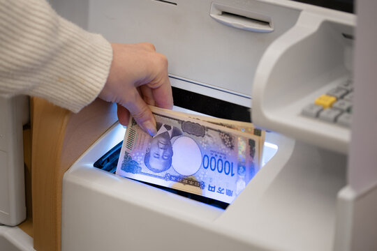 銀行やコンビニのATMで一万円札（新紙幣）を入出金する女性の手元