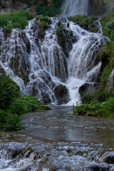Waterfall cascading over rocky ledges amid greenery © Luigi
