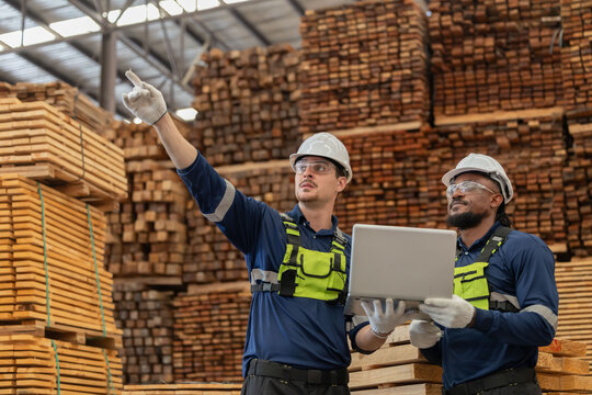 Workers discuss tasks in a warehouse with pallets stacked high in the background